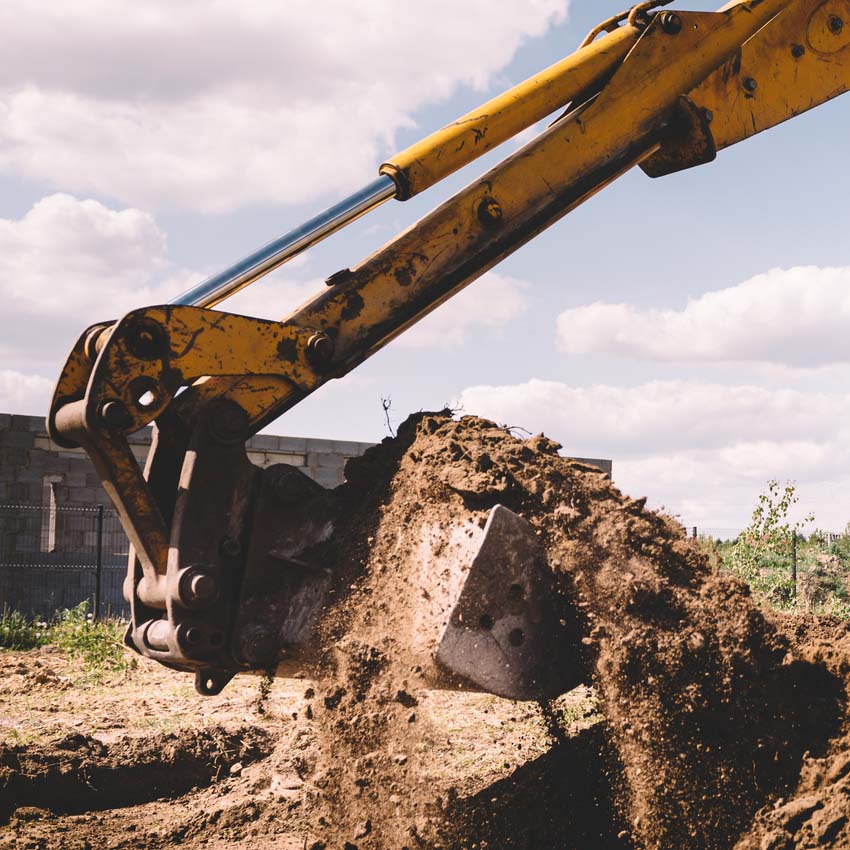 Backhoe arm and bucket full of rigged dirt